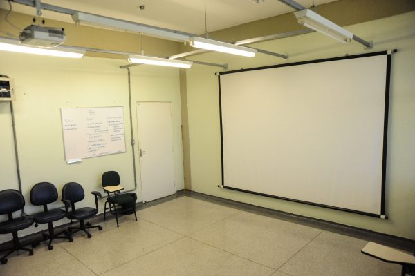 Sala de aula com quadro branco e projetor multimídia.