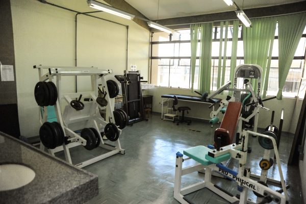 Sala com equipamentos de musculação e anilhas de peso.